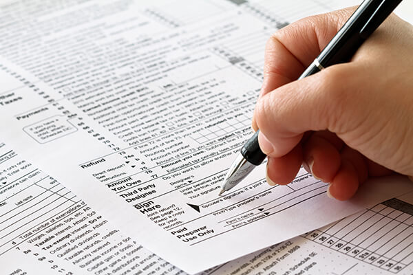 person filling out paper tax return form - payments on account
