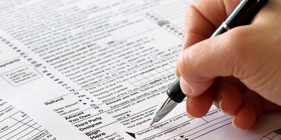 person filling out a paper tax return form