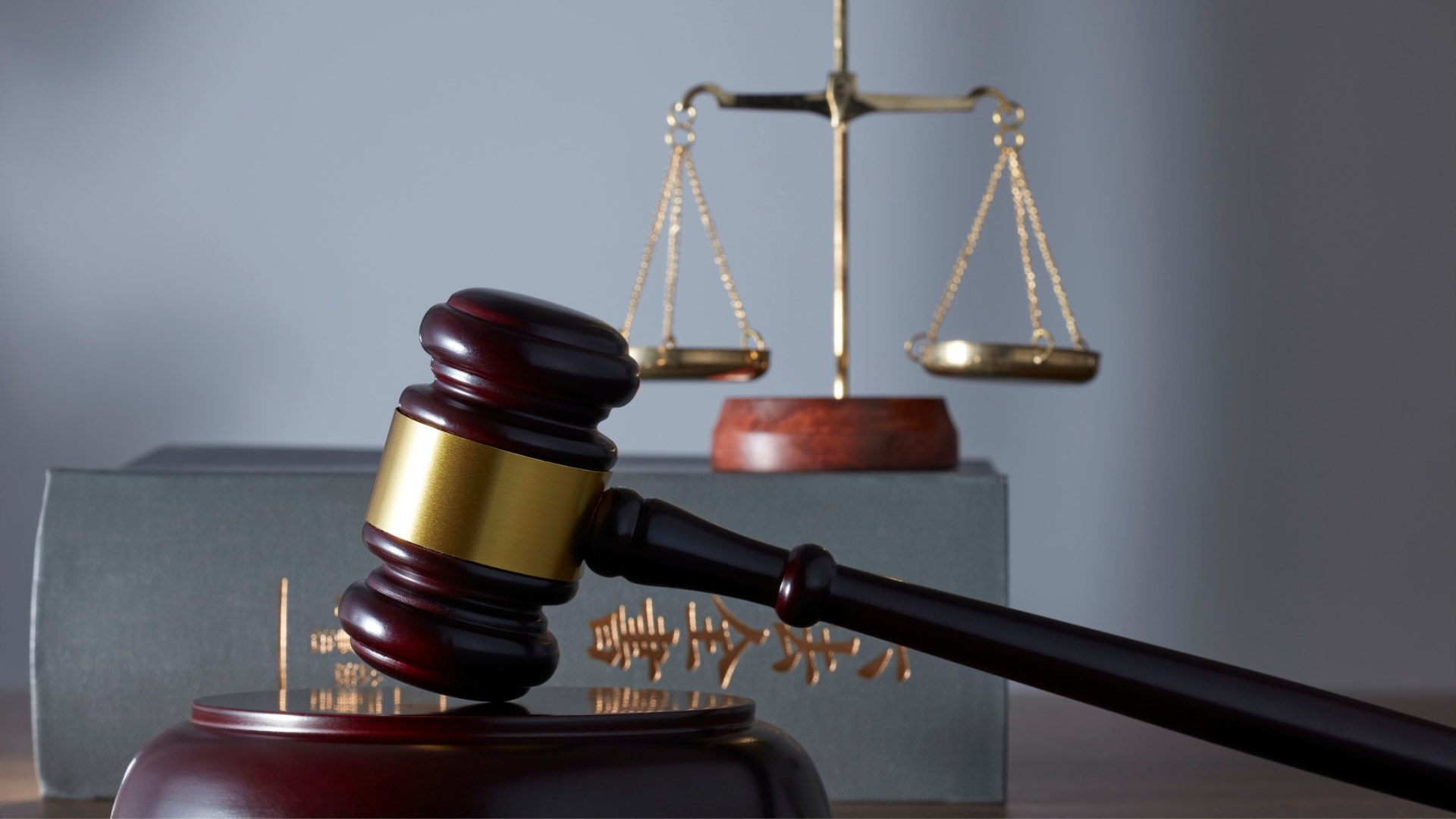 A top-down photograph of a person in a white shirt working on a silver and black laptop on a dark, wood-grain desk. To the left of the laptop are several black and white office supplies, including a black spiral notebook, a white wallet, a desk organizer with a pencil, paper clips, and sticky notes, and a partially visible tablet or phone at the bottom. A white cup of coffee is near the top right. Property Tax Advice Expat Tax Advice PTA ETA Riverview Portfolio