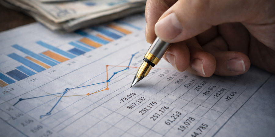 Close-up of a person reviewing a financial report with charts and numerical data using a pen, representing accurate financial reporting and financial analysis.