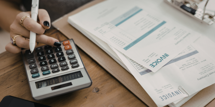 Calculator beside business invoices representing rising UK tax receipts and tax planning for SMEs.