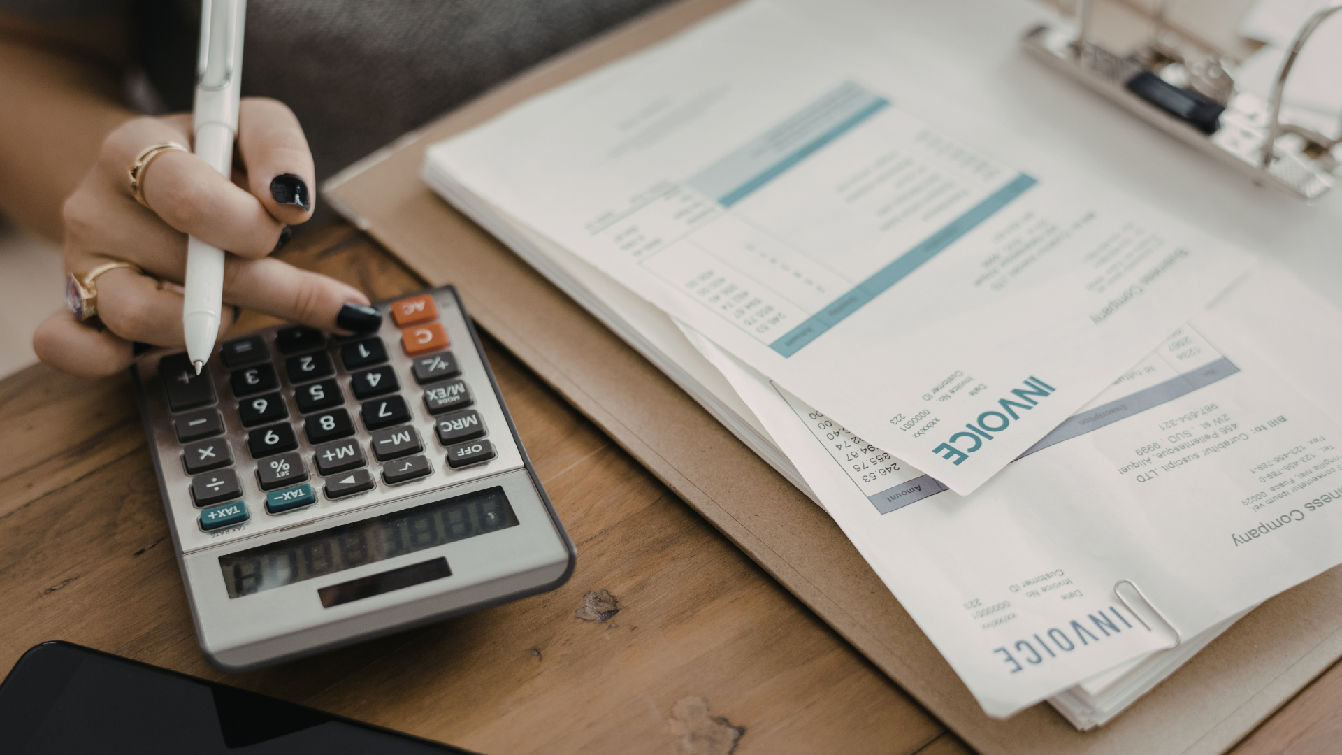 Calculator beside business invoices representing rising UK tax receipts and tax planning for SMEs.